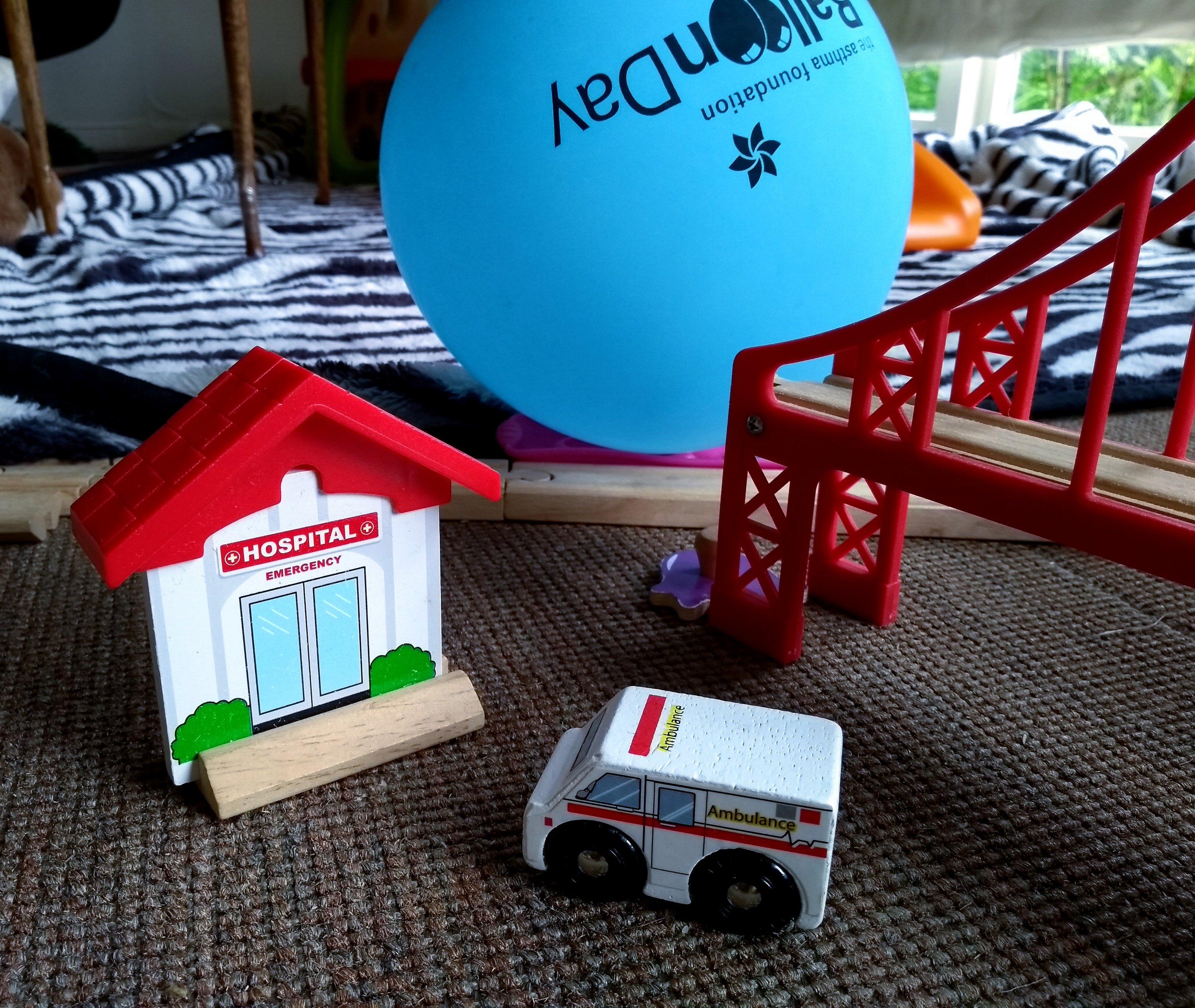Toy hospital and ambulance on carpeted floor with balloon